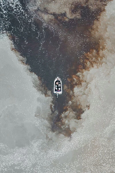 Drone photo looking down on a speedboat between clouds of sediment flowing down the Mary River, Northern Territory, Australia