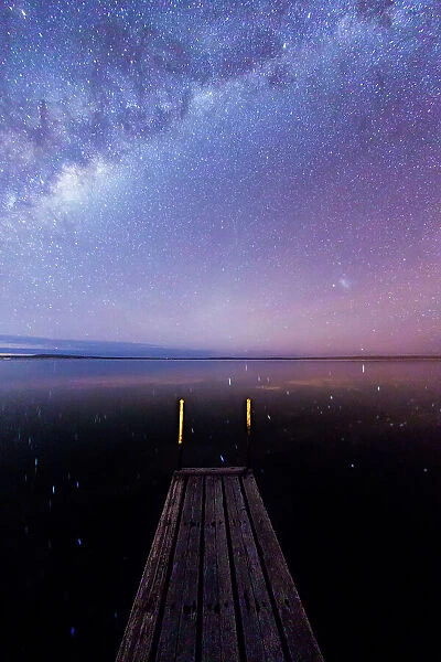 Milky Way and stars over the Proper Bay. Small wooden jetty and stars reflecting in the ocean. Port Lincoln. Eyre Peninsula. South Australia