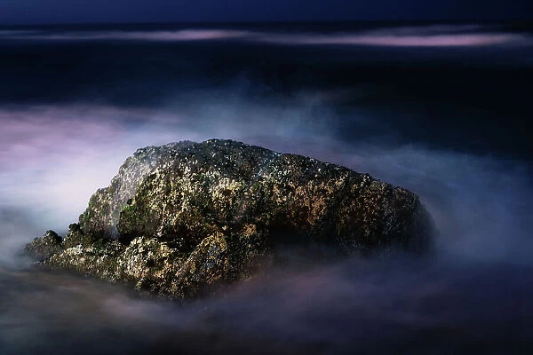 A Night View of a Rock in the Middle of the Sea Waves in a Long Exposure View