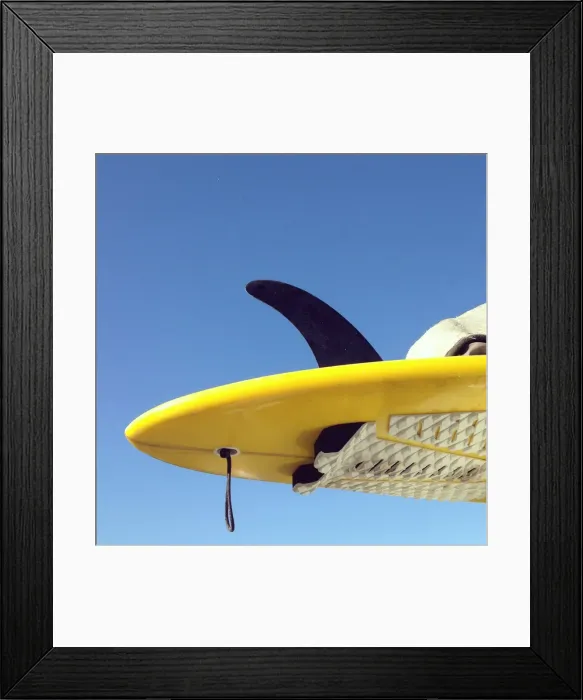 Framed Print : Looking up at surfboard tail against a blue sky