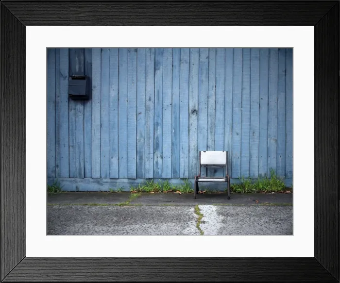 Framed Print : Chair in front of blue fence