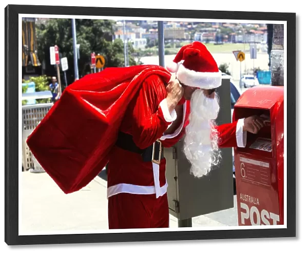 Man dressed as Santa Claus putting letter in mail box, side view