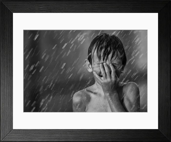 Framed Print : Boy playing in the sprinklers on a hot summer day