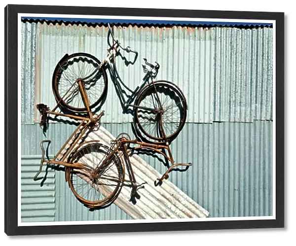 Three bike artwork hanging from a tin shed