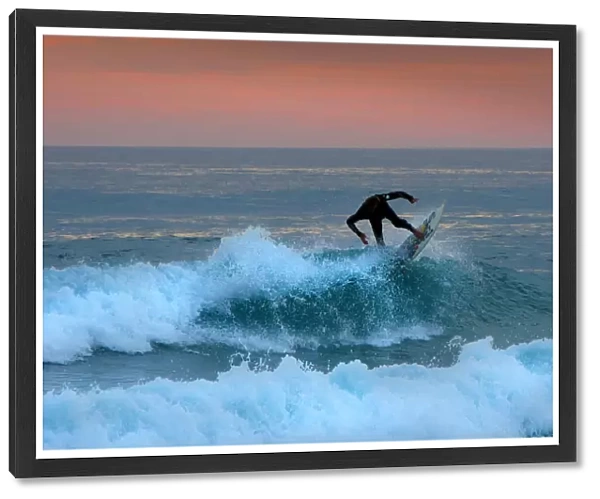 A lone surfer rides a wave at Woolami Beach and coastline, Phillip Island, Victoria, Australia