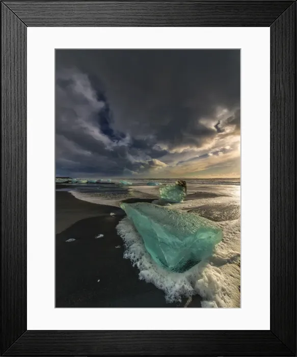Framed Print : Jokulsarlon Beach in winter, just after a huge storm hit the coastline. Ice bergs from the nearby lagoon have been swept up onto the coastline and surge in and out with the tide