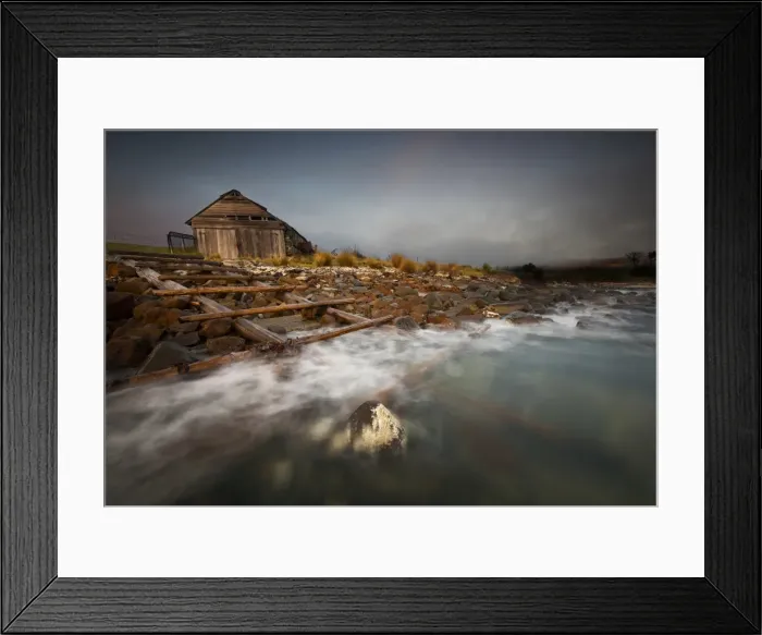 Framed Print : Old boat shed with waves and rocks