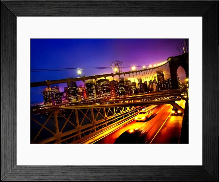 Framed Print : A tilted view of a yellow cab speeding along the Brooklyn Bridge at dusk