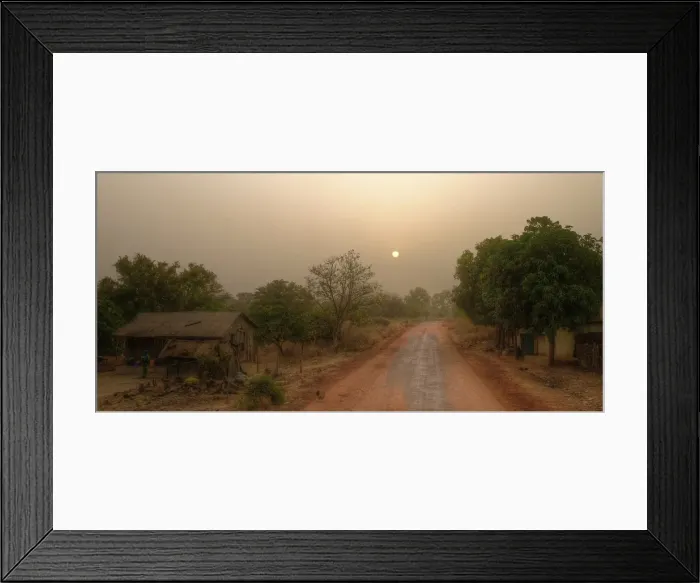 Framed Print : Local road in rural Gambia with farmhouse, forest and sunrise sun on hazy morning