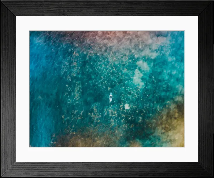 Framed Print : Aerial view of a female surfer on the ocean looking at the camera Framed Print : Aerial view of a female surfer on the ocean looking at the camera