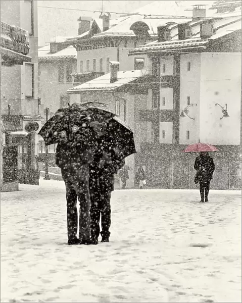 Snow talk. A lady with a red umbrella walking in heavy snowfall