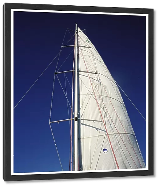 A boat sail and mast against blue sky