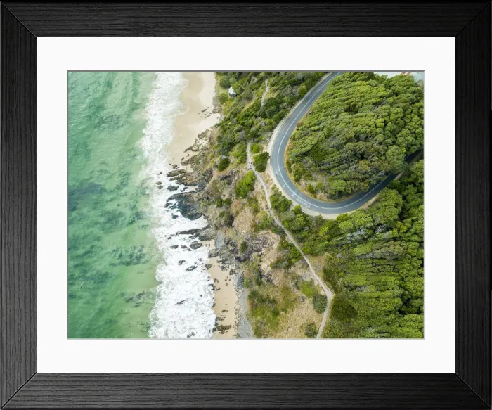 Framed Print : rocky outcrop into ocean with road