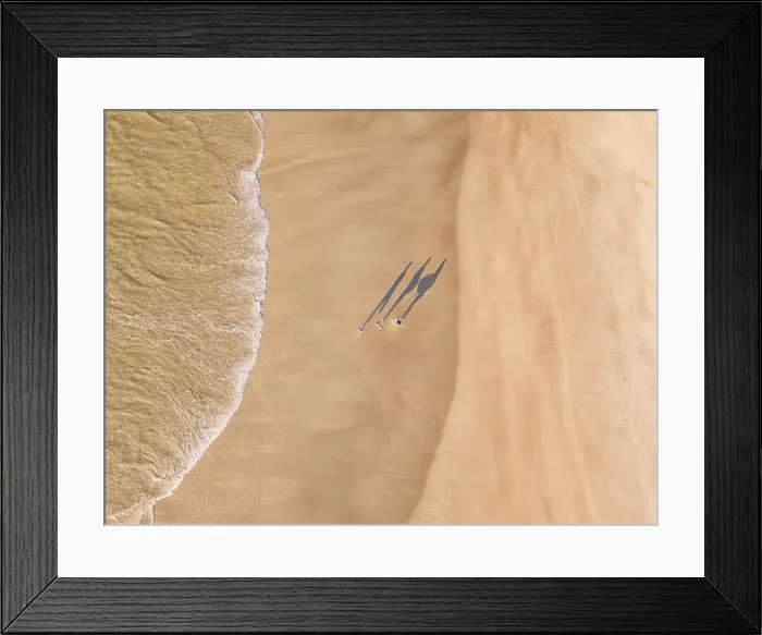 Framed Print : Aerial shot above a surfers walking along the beach Framed Print : Aerial shot above a surfers walking along the beach