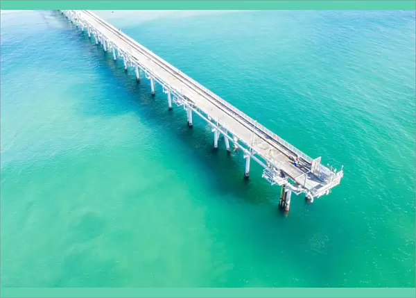 Drone view of a Long sand pumping jetty out into the clear ocean water
