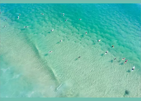 Aerial point of View crystal clear ocean waters with people surfing