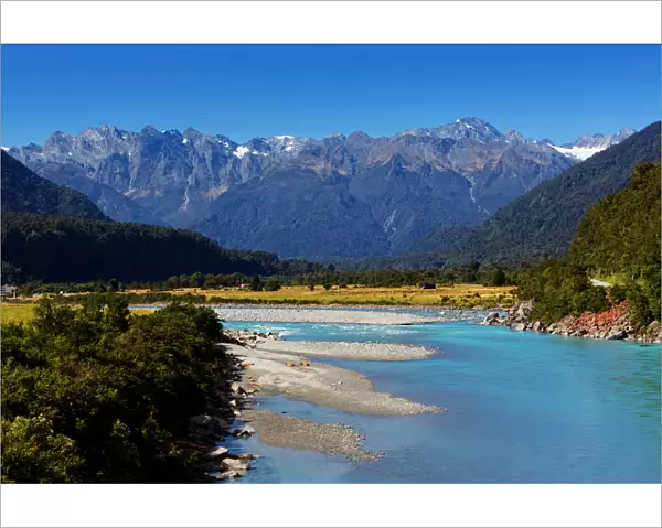 Turquoise-colored Whataroa River with snowcapped Southern Alps on horizon on autumn