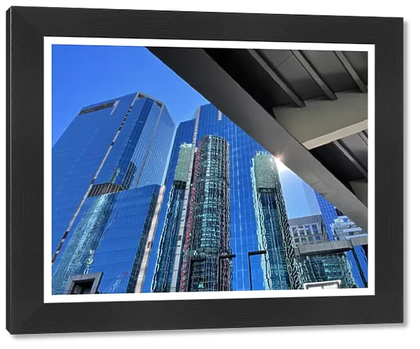 Glass skyscrapers, office buildings, elevated walkway bridge, lens flare, blue sky
