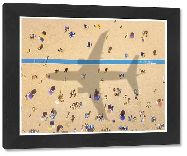 Aerial view of an airplane shadow over a crowded sandy beach