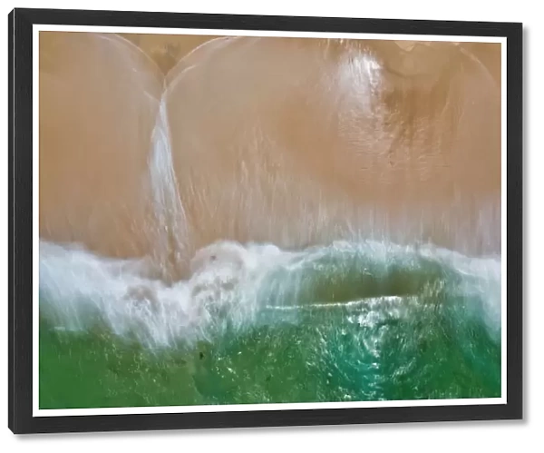 Aerial view of turquoise water crashing onto a sandy beach - Long Exposure