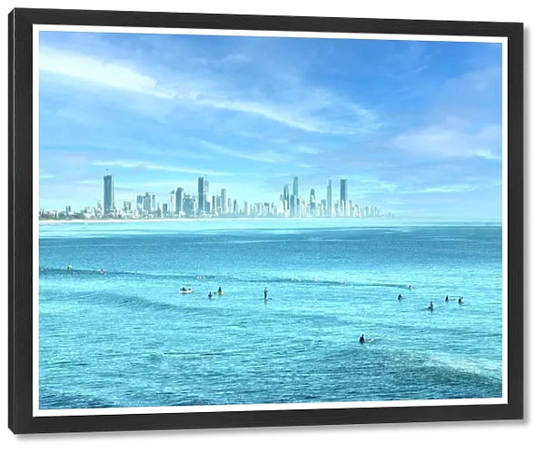 People surfing in the blue ocean waters of the Gold Coast with city skyline