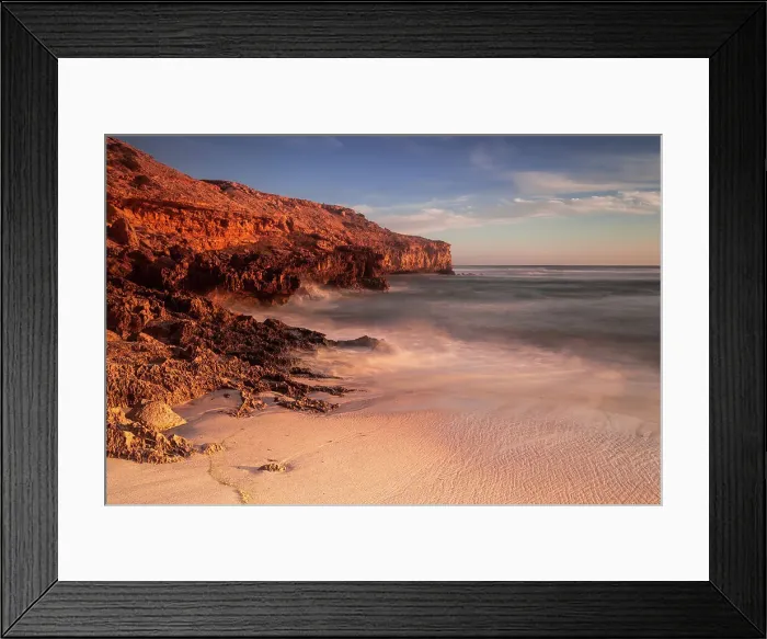 Framed Print : Red glow. Sunset on the coast with red cliffs and warm colours on the beach
