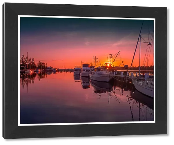A summer dawn light castes a glow over the boats and harbour area at Lakes Entrance, East Gippsland