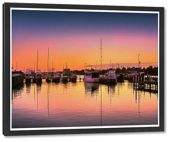 A summer dawn light castes a glow over the boats and harbour area at Lakes Entrance, East Gippsland