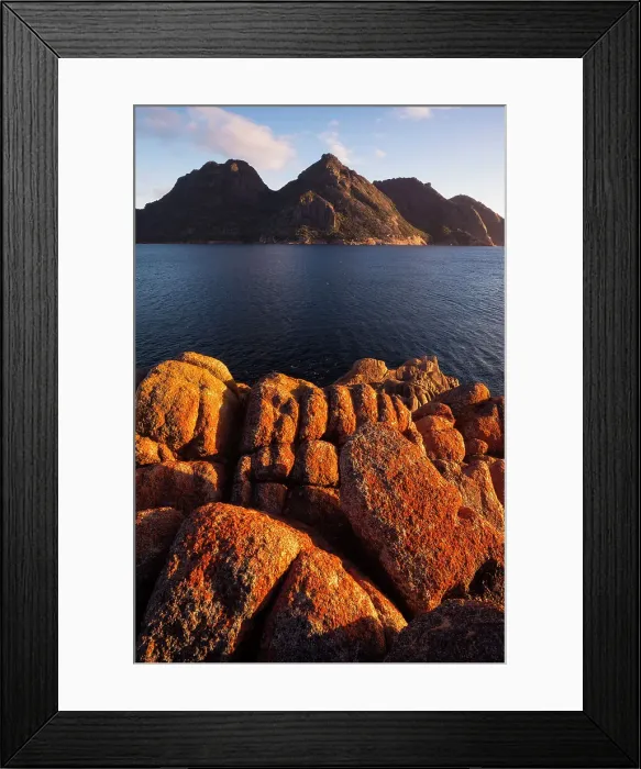 Framed Print : Sunrise at Wineglass Bay lights up lichen covered boulders with the Hazards mountain range beyond, Freycinet National Park, Tasmania, Australia