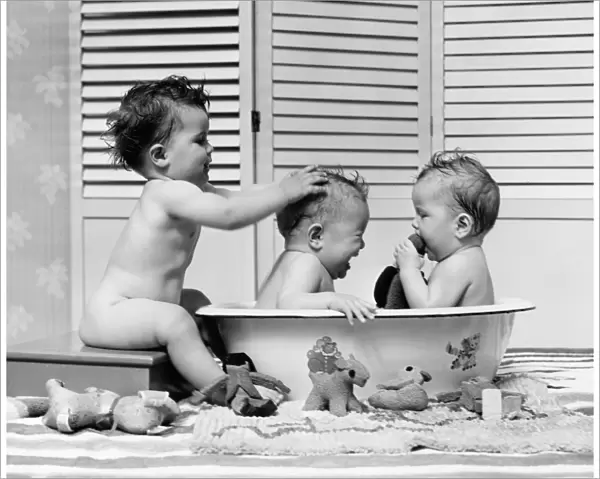 Three babies in wash tub, bathing