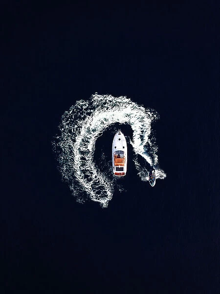 Aerial view of a jet ski swirling around a recreational boat