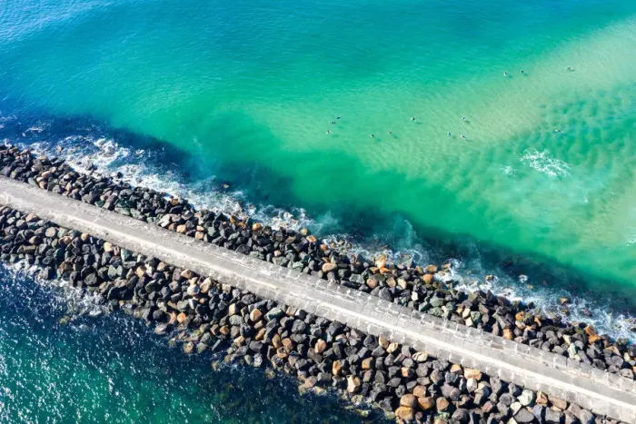 Framed Print : Aerial View of rock walkway out into the ocean with surfers Framed Print : Aerial View of rock walkway out into the ocean with surfers