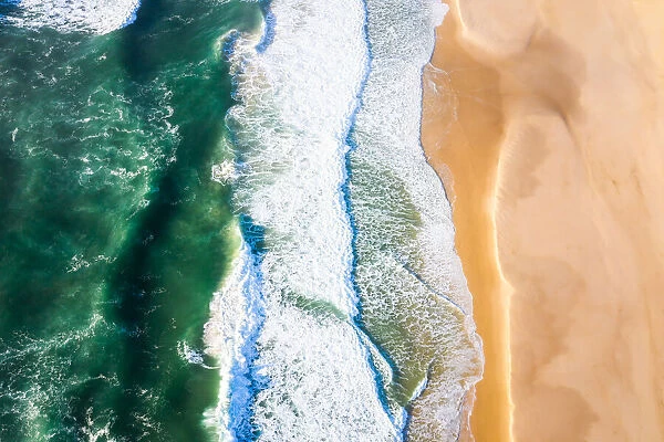 An aerial view of waves crashing on a beach, New South Wales in the morning