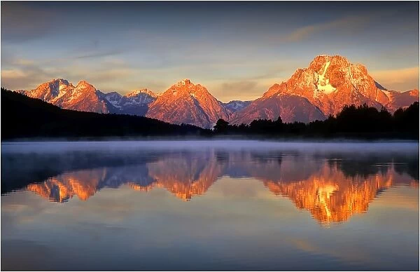 A beautiful coloured dawn casts its glow over Jackson lake in the Grand Tetons, Wyoming