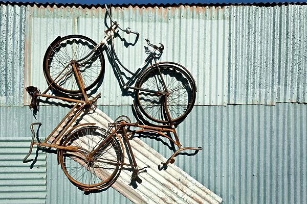 Three bike artwork hanging from a tin shed