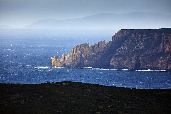 Blue seascape with sun illuminated rocky headland, Cape Raoul, Tasmania, Australia