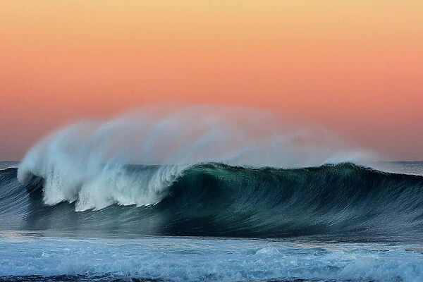 breaking wave with sunset colours in the sky