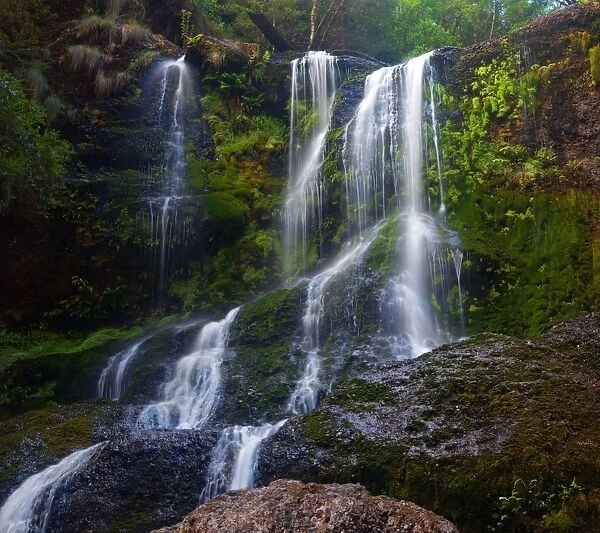 Cascading waterfall over green rocks