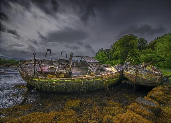 Derelict old fishing trawlers, moored along an old stone wharf on the Isle of Mull, Inner Hebrides, Scotland