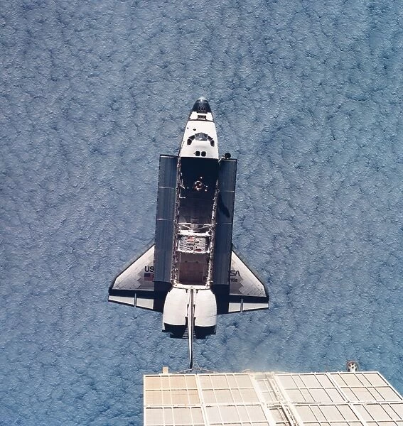 Elevated view of the space shuttle orbiting above earth with its cargo bay open