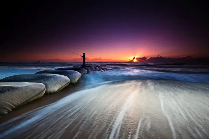 Framed Print : Fisherman standing on huge sandbags