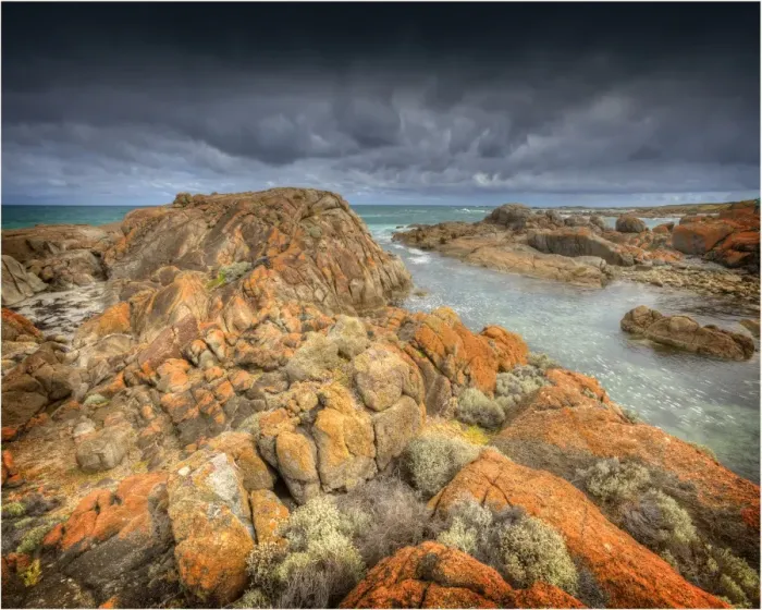 Framed Print : Half moon bay on the West coastline of King Island, has large rock-pools and magnificent red coloured lichen boulders of pink granite. Bass Strait, Tasmania