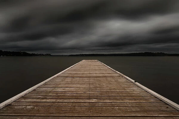 jetty out onto the lake with dark moody clouds