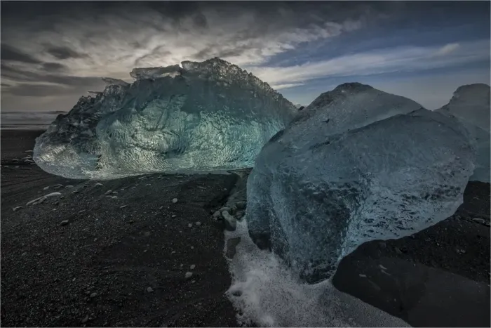 Framed Print : Jokulsarlon Beach in winter, just after a huge storm hit the coastline. Ice bergs from the nearby lagoon have been swept up onto the coastline and surge in and out with the tide