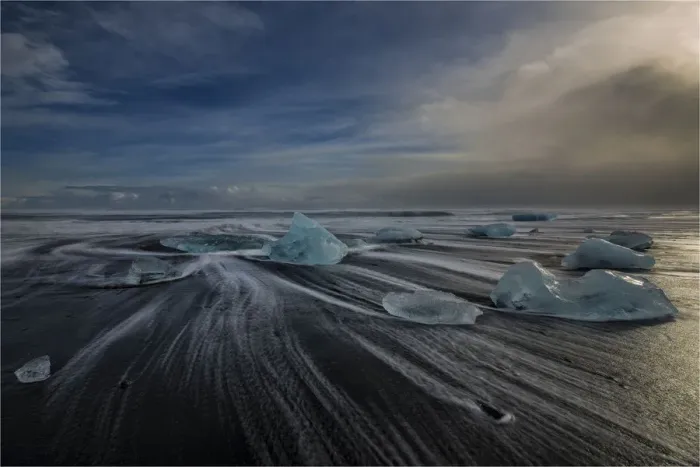 Framed Print : Jokulsarlon Beach in winter, just after a huge storm hit the coastline. Ice bergs from the nearby lagoon have been swept up onto the coastline and surge in and out with the tide