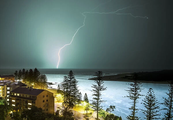 A lightning strike hits the surface of the water in the distance