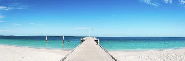 Long concrete pier leading out into blue ocean