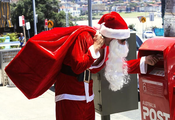 Man dressed as Santa Claus putting letter in mail box, side view