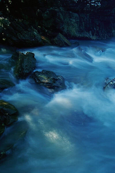 New South Wales, Australia. Blue pastel water breaks over rocks at Bittangabee Bay