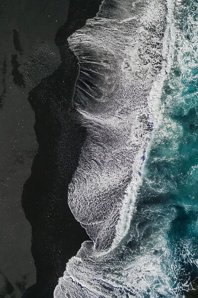 Ocean waves crashing onto volcanic sands as seen from above, Lanzarote